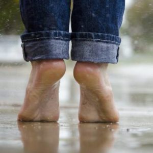 Bare feet standing on a wet surface at the beach, representing everyday foot health