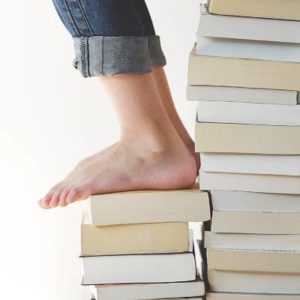 Bare foot stepping on a stack of books, representing foot health and everyday balance